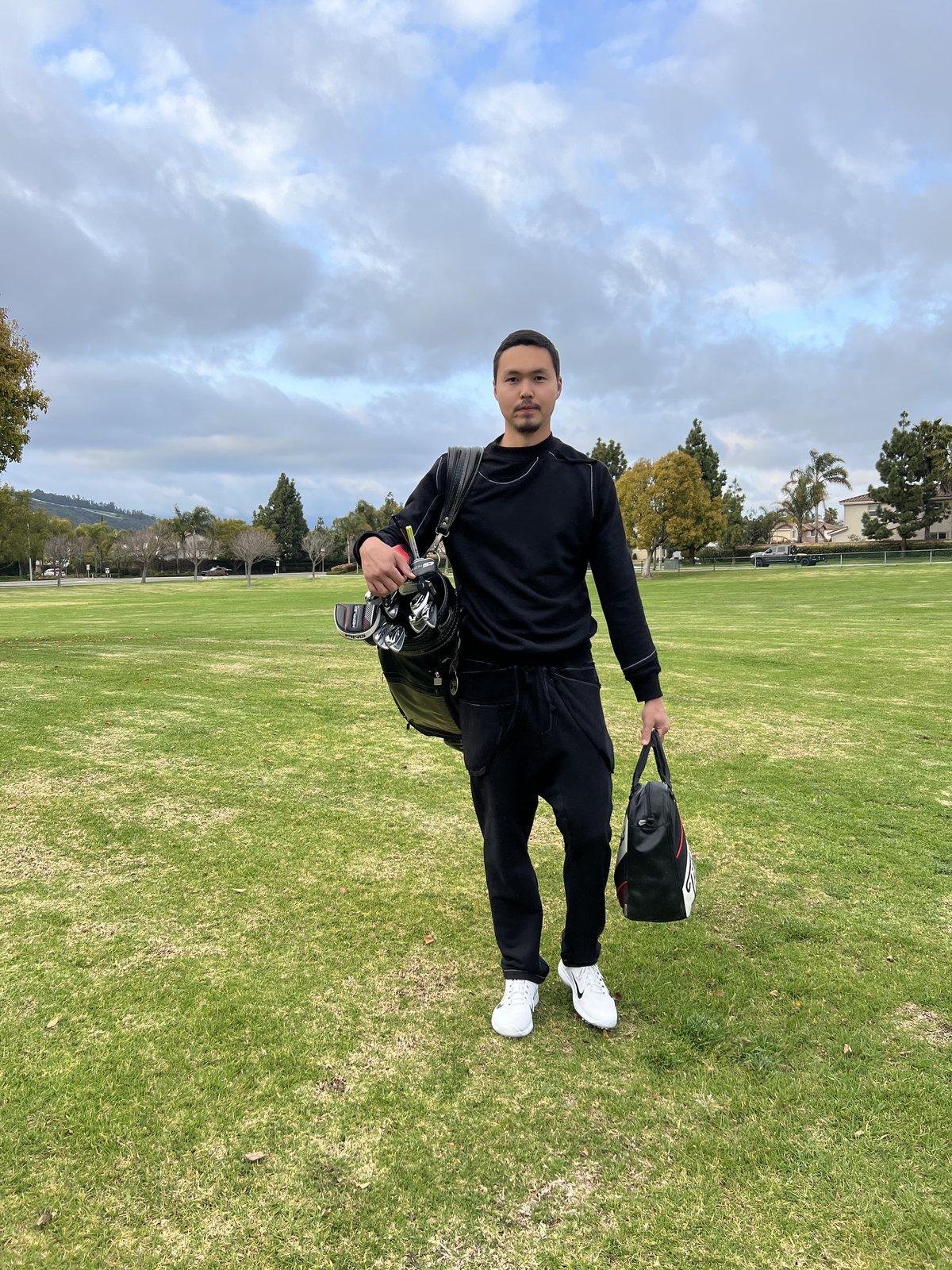 Nurtai carrying his golf bag across a park in California